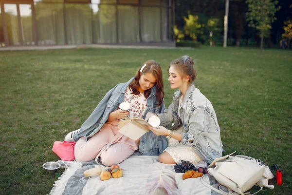 Κορίτσια που κάθονται σε μια κουβέρτα σε ένα καλοκαιρινό πάρκο — Φωτογραφία Αρχείου