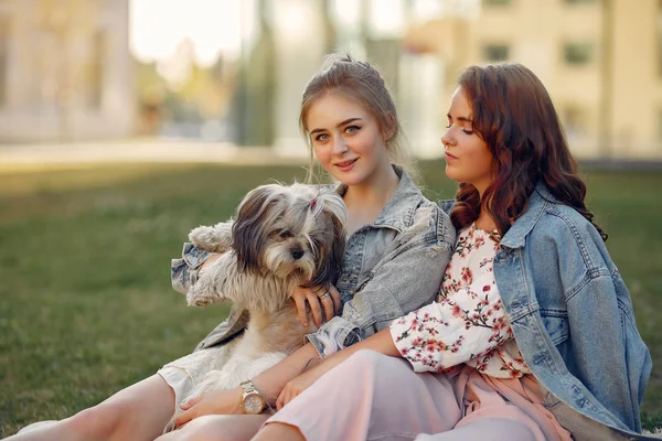 Dos chicas sentadas en un parque con un perrito —  Fotos de Stock