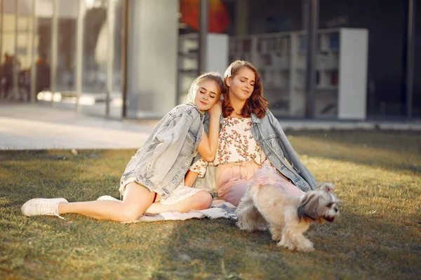 Дві дівчини сидять в парку з маленьким собакою — стокове фото