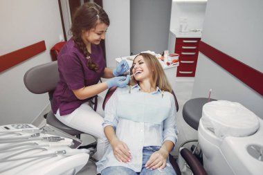 Güzel kız dişçi ofisinde oturuyor.