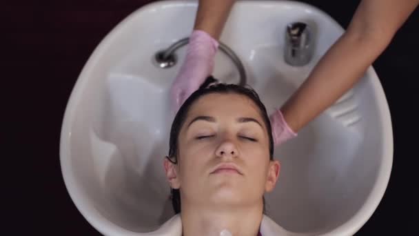 Stylist washing clients hair in sink in beauty salon — Stock Video