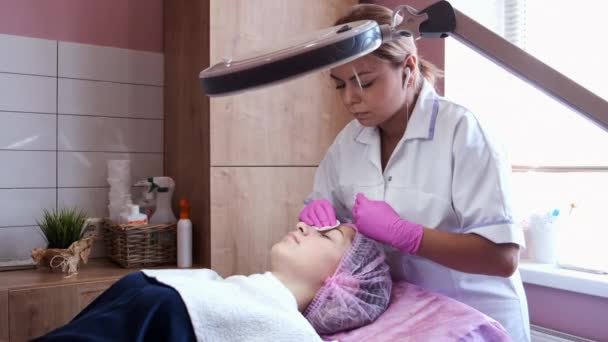 Cosmetologist wipes face of young woman with cotton pads — Stock Video