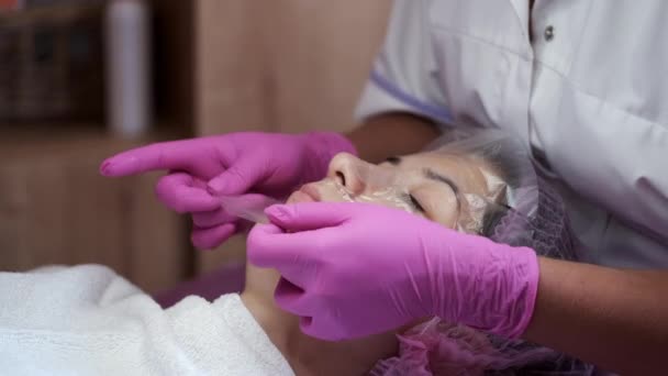 Cosmetologist wipes face of young woman with cotton pads — Stock Video