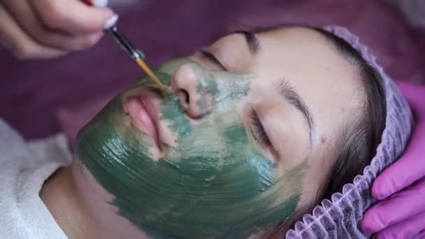 Обрезанный вид процесса нанесения маски на лицо клиента в салоне — стоковое видео