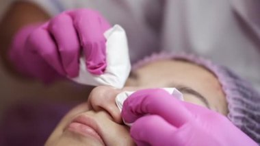 Cosmetologist doing manual facial cleansing in beauty salon