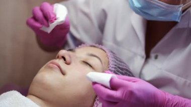 Cosmetologist doing manual facial cleansing in beauty salon