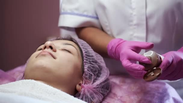 Kosmetolog nanáší krém na obličej a masíruje ženu v salonu — Stock video