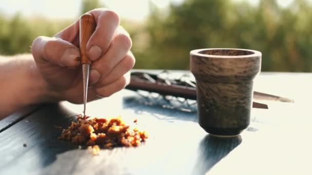 Gekropte weergave van de bereiding van tabak voor shisha op tafel buiten — Stockvideo