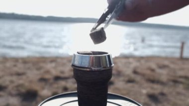 Cropped view of process of lighting coal in hookah outside