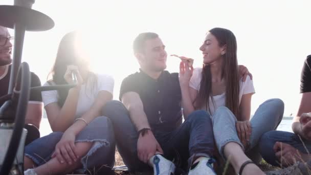 Jóvenes comiendo pizza fumando shisha afuera — Vídeo de stock