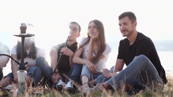 Группа молодых людей, сидящих снаружи и курящих шишу — стоковое видео