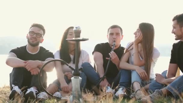 Group of young people sitting outside smoking shisha — Stockvideo