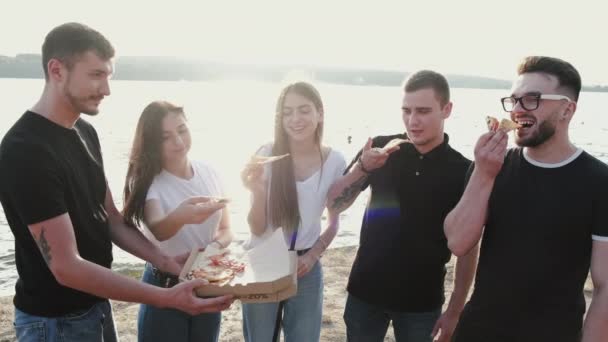Молодые люди едят пиццу, куря шишу снаружи — стоковое видео