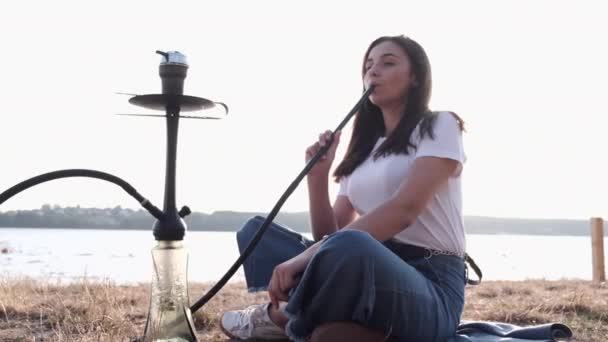 Woman holding pipe smoking shisha alone outside — Stok video