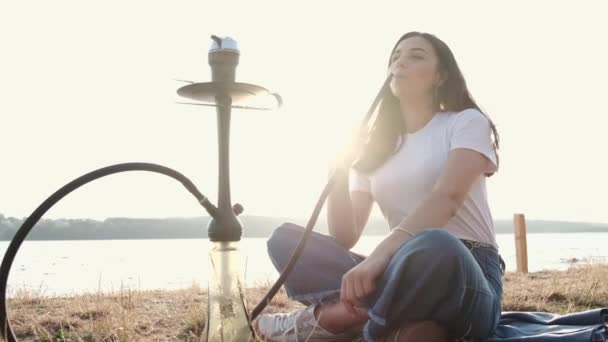 Woman holding pipe smoking shisha alone outside — 图库视频影像