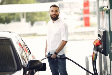 Yakışıklı adam bir depo arabaya benzin dolduruyor.