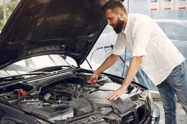 Yakışıklı adam arabasının motorunu kontrol ediyor.