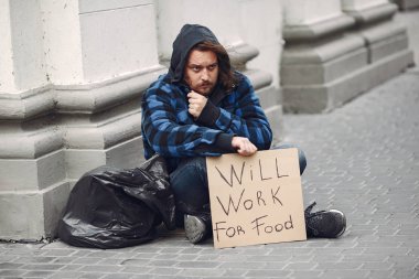 Güz şehrinde durgun elbiseli evsiz bir adam.