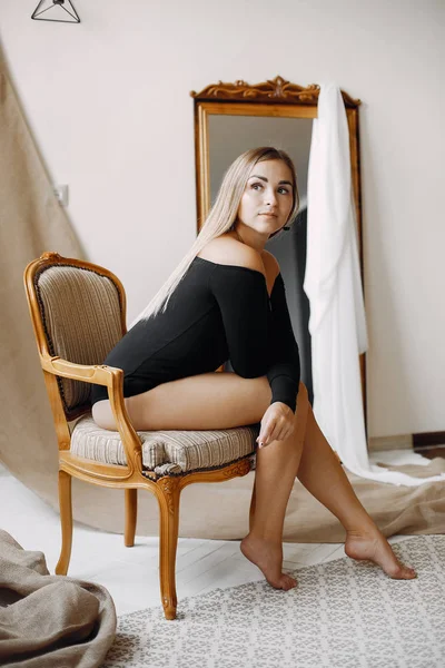 Elegante Frau mit blonden Haaren sitzt in einem Studio — Stockfoto