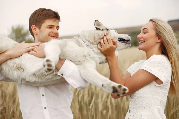 Coppia in un campo autunnale che gioca con un cane — Foto Stock