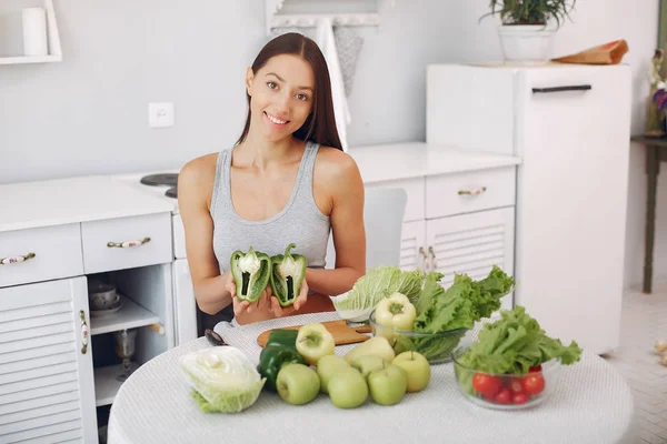 Menina bonita e desportiva em uma cozinha com um legumes — Fotografia de Stock