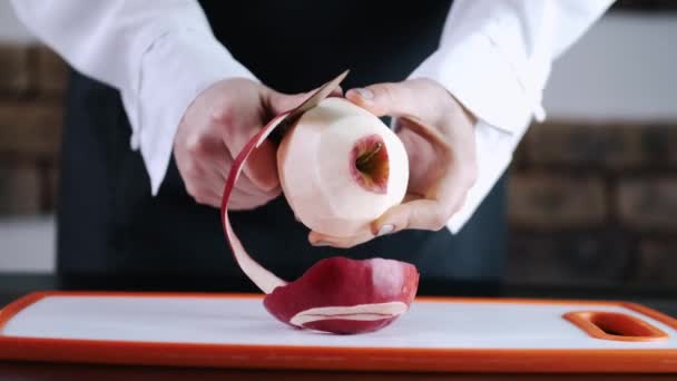 La jugosa fruta de manzana está siendo pelada en una tabla de cortar — Vídeo de stock