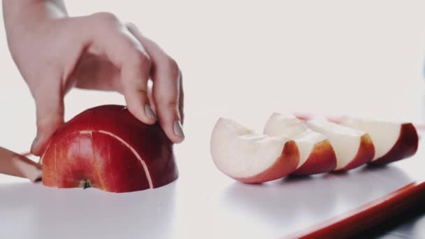 The juicy apple fruit is being cut on a cutting board — Stockvideo