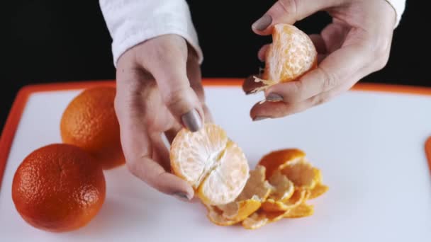 The mandarin fruit is being peeled over a cutting board — Stockvideo