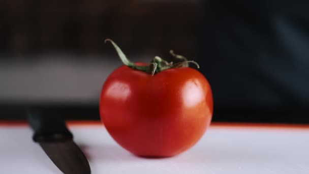 A fresh tomato is being cut with a knife — Stok video