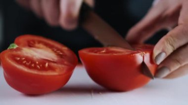 A fresh tomato is being cut on a cutting board