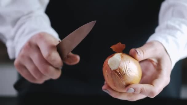 O chef está descascando uma cebola com uma faca — Vídeo de Stock