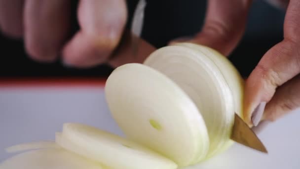 The onion is being sliced with a knife — Stock videók