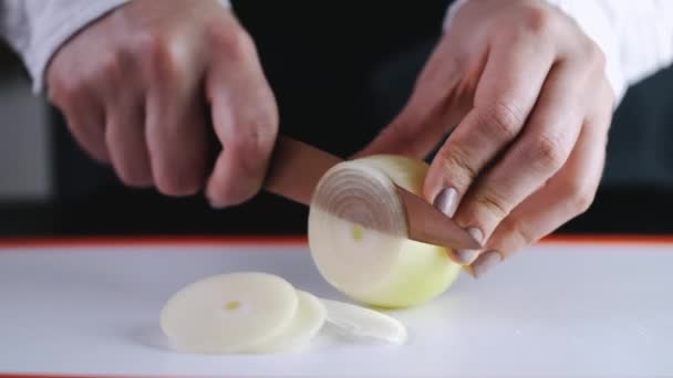 Die Zwiebel wird mit einem Messer in Scheiben geschnitten — Stockvideo