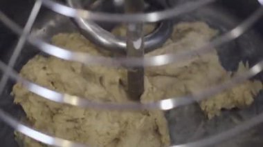The pastry is being made in a mixing bowl by an automatical tool
