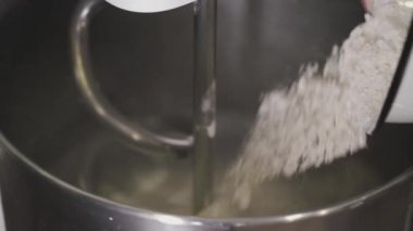 The flour is being stirred by a mixer in a bowl