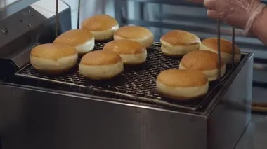 The fried donuts are being taken out of a deep fryer