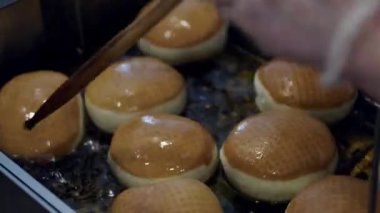 The soft donuts are being fried in a deep fryer