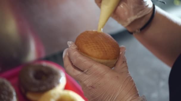 El donut horneado está siendo rellenado por un panadero — Vídeos de Stock