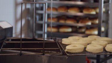 The donut-shaped pastry is being put into a deep fryer