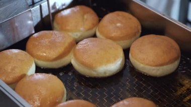 The crumby bases for donuts are being fried in a fryer.