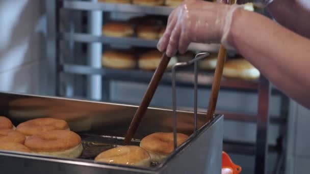 Шеф-повар крутит пончики палками во время жарки. — стоковое видео