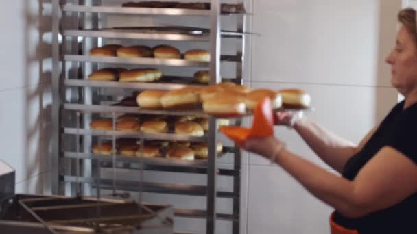 Шеф-повар кладет жареные пончики на специальную полку — стоковое видео