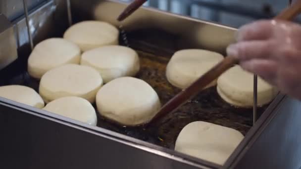 Die Donuts werden in einer Fritteuse gebraten — Stockvideo
