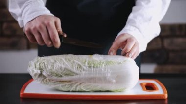 A cauliflower in a cling film is on the board