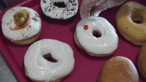 De gebakken donuts worden versierd met snoep. — Stockvideo