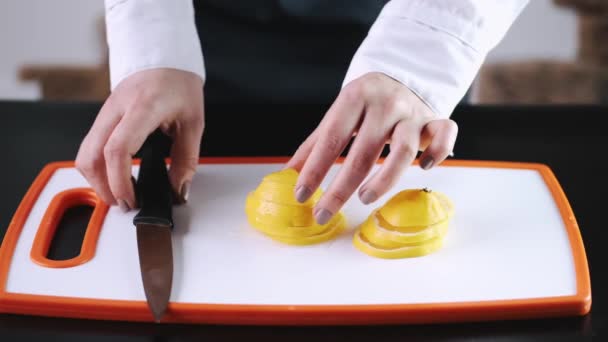 The orange is being cut on a cutting board — ストック動画