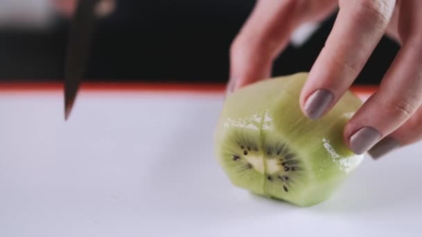 O kiwi está sendo cortado em uma tábua de corte — Vídeo de Stock