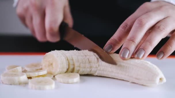 O chef está cortando uma banana em uma tábua de corte — Vídeo de Stock