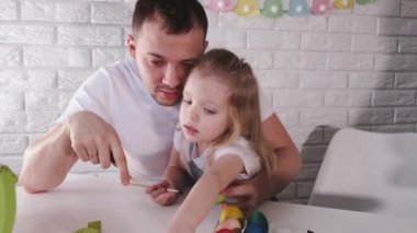 Baba ve küçük kızı paskalya yumurtalarını fırçayla renklendiriyorlar..