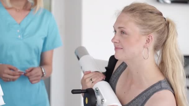 Женщина на физиотерапии делает физические упражнения с квалифицированным терапевтом — стоковое видео